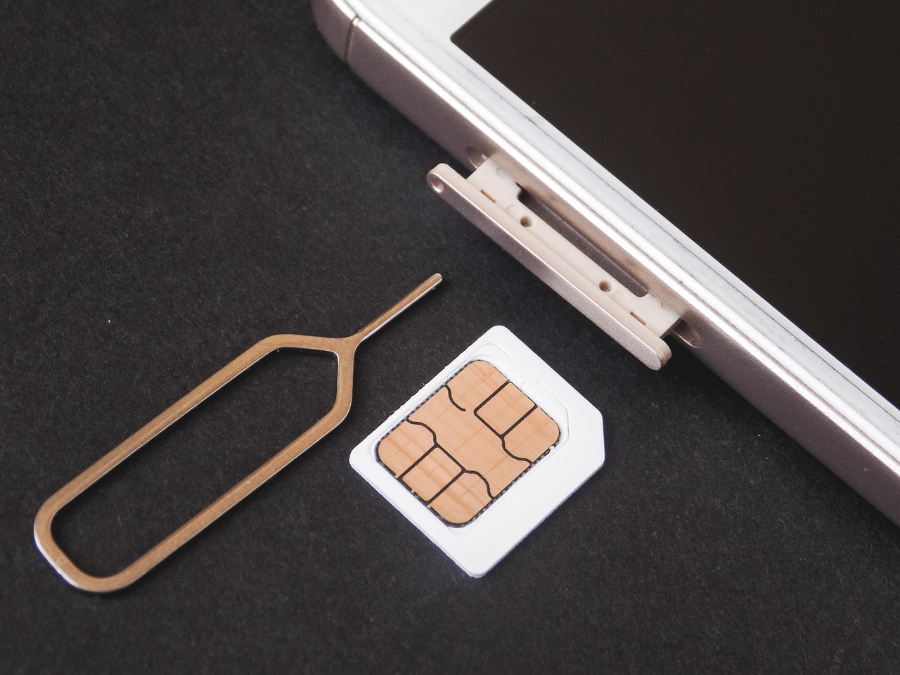 スマートフォンのSIMトレイにSIMカードを挿入する様子