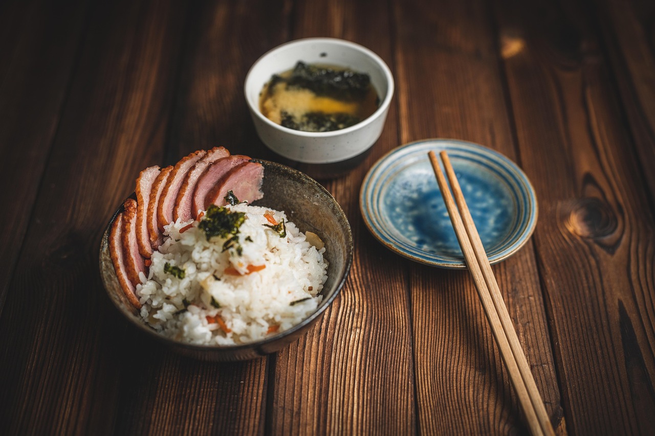 ご飯と焼いた肉、味噌汁を木のテーブルに並べた和食膳