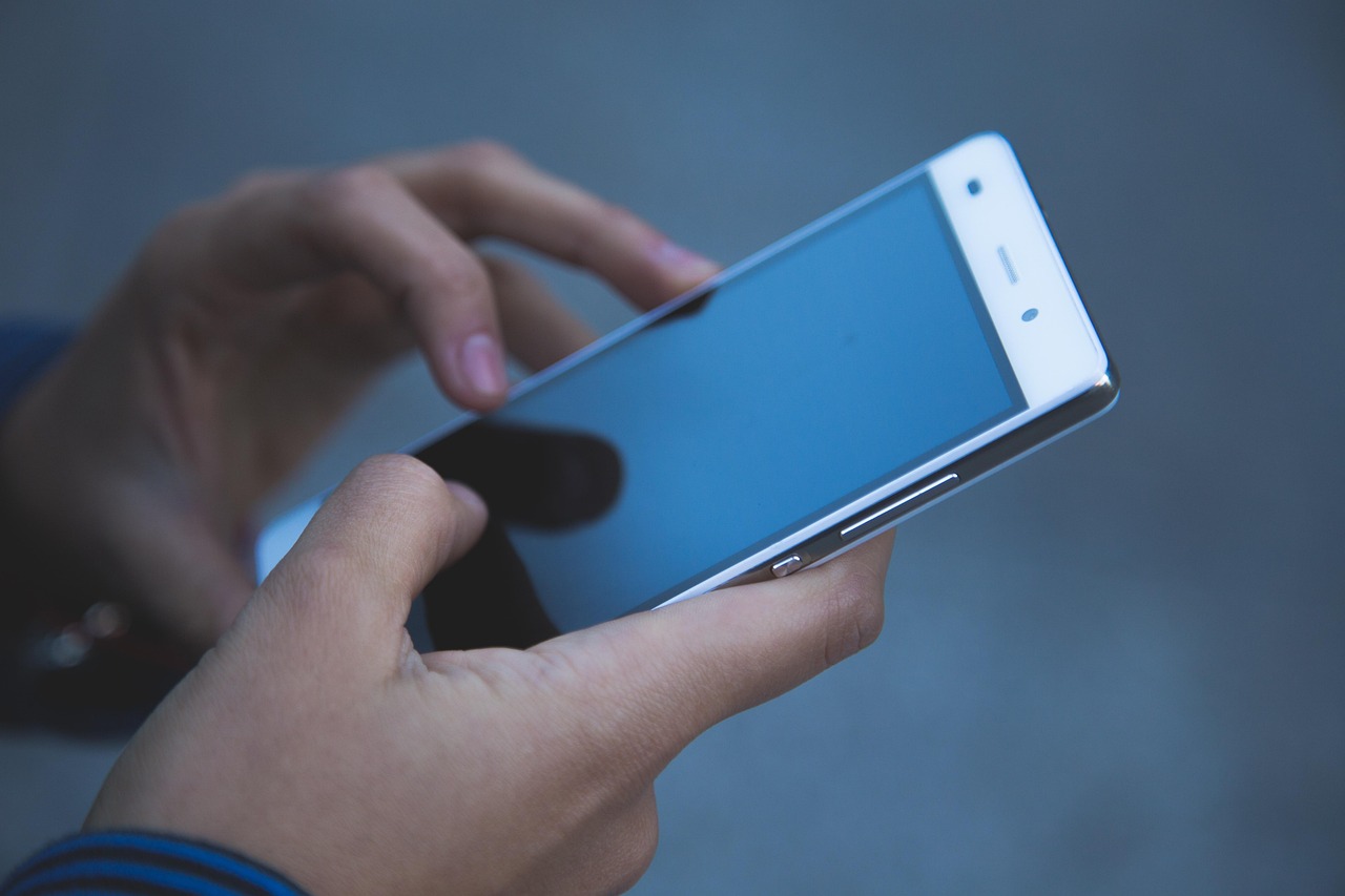 スマートフォンの画面を指で操作している手元