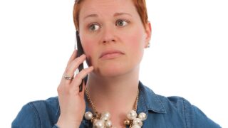 心配そうな表情でスマートフォンを耳に当てて通話している女性のイメージ