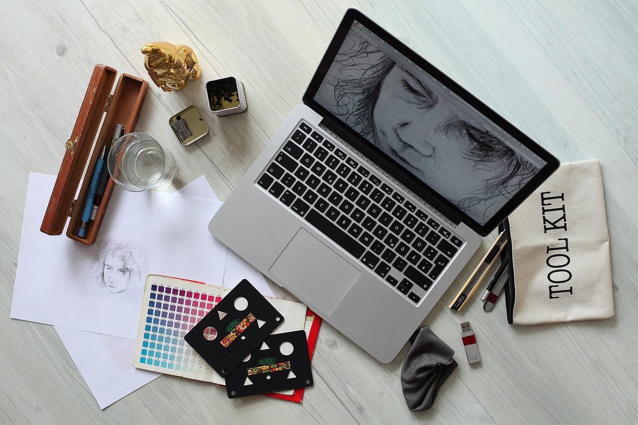 ノートパソコンの画面にイラストを表示し、周りにデザインツールが並んでいる様子