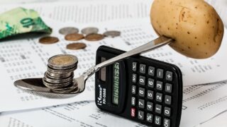 スプーンに乗ったコインと計算機で家計のやりくりを表したイメージ