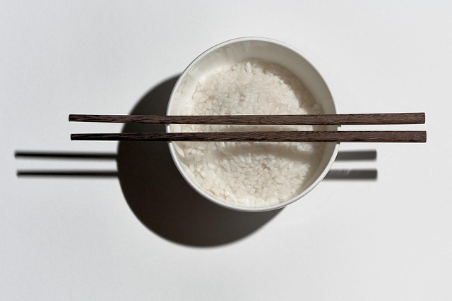 お茶碗に盛られた白いご飯に箸を渡した写真、コメの価格上昇をイメージ