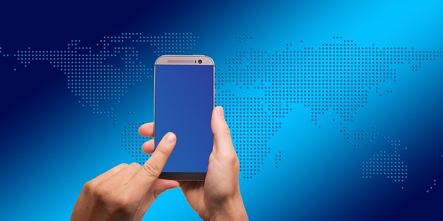 海外の地図を背景にスマートフォンを操作する手元、為替や国際経済の動きをイメージした写真