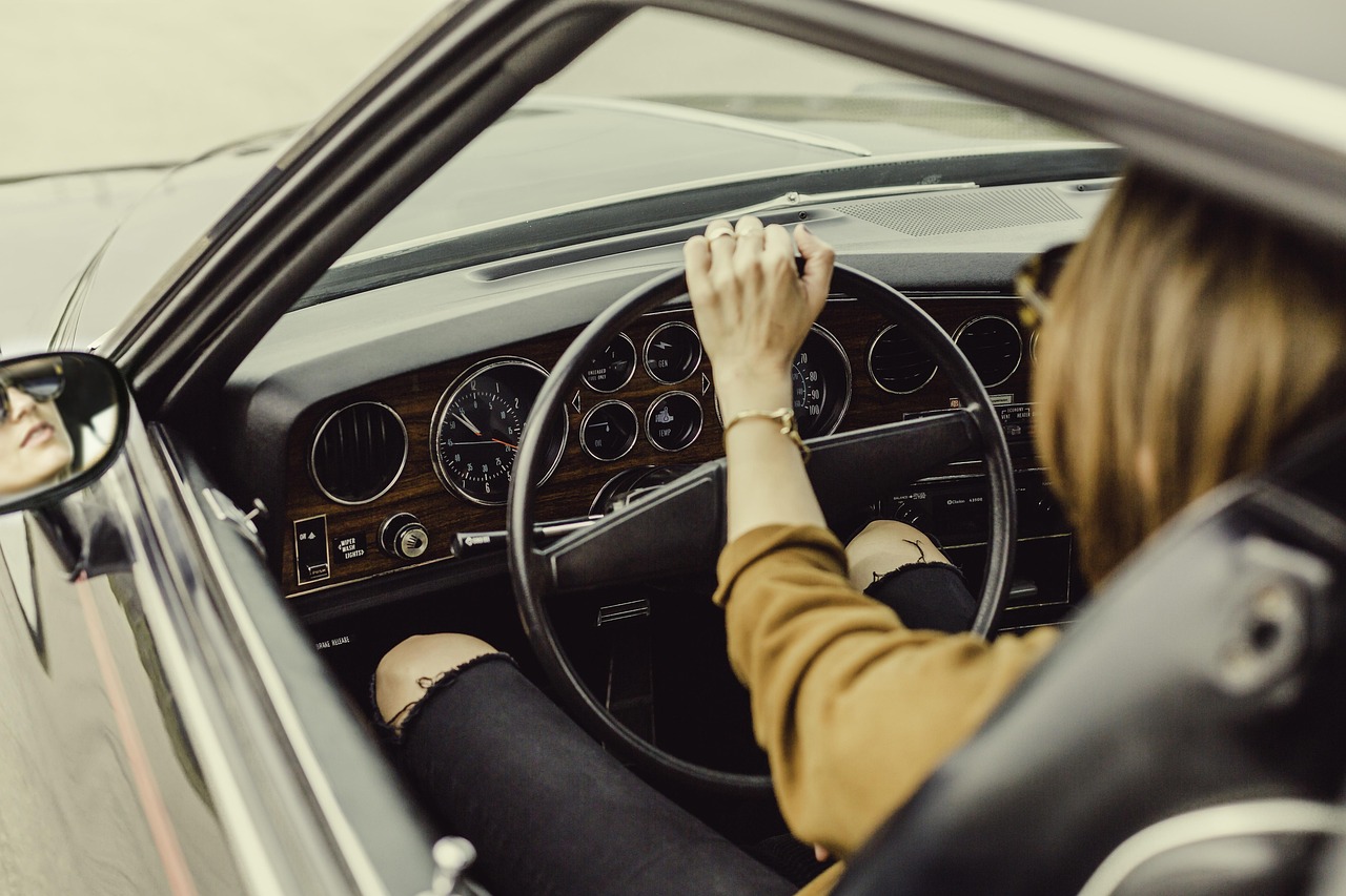 車を運転する人の手元とダッシュボードの写真、自動車や移動にまつわるお金の話をイメージ