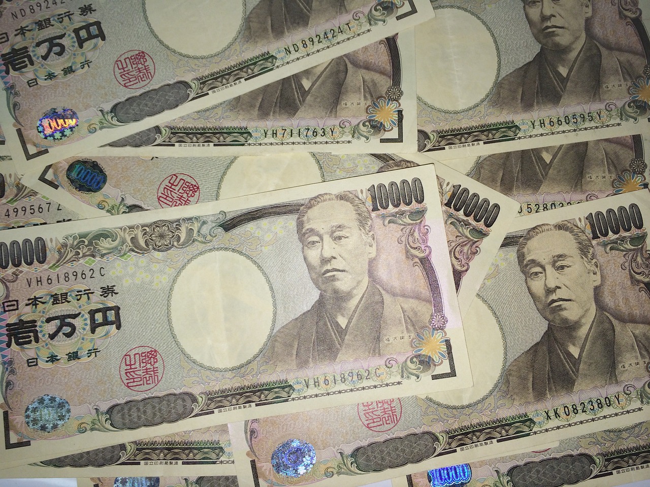 重なり合った日本円の一万円札の写真、為替や物価の動きをイメージ