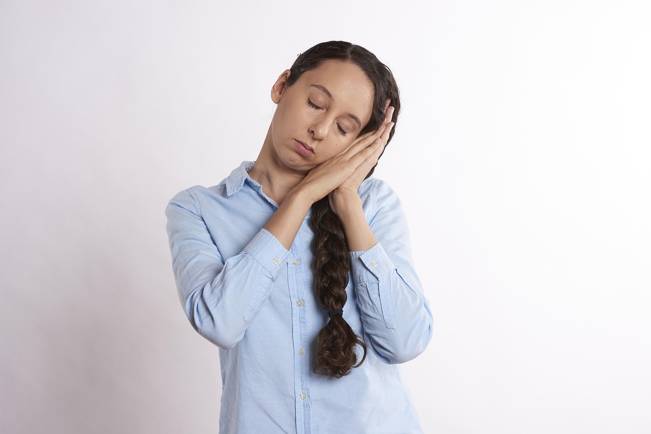 手に頬を預けて目を閉じ、強い眠気に襲われている女性の様子