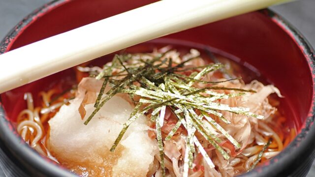 ねぎと薬味がたっぷりのった温かいそばの写真