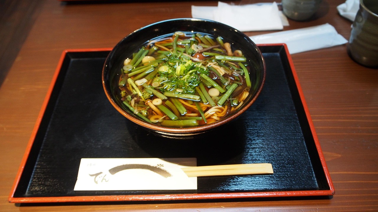 野菜や薬味がたっぷり入った温かいそばの写真