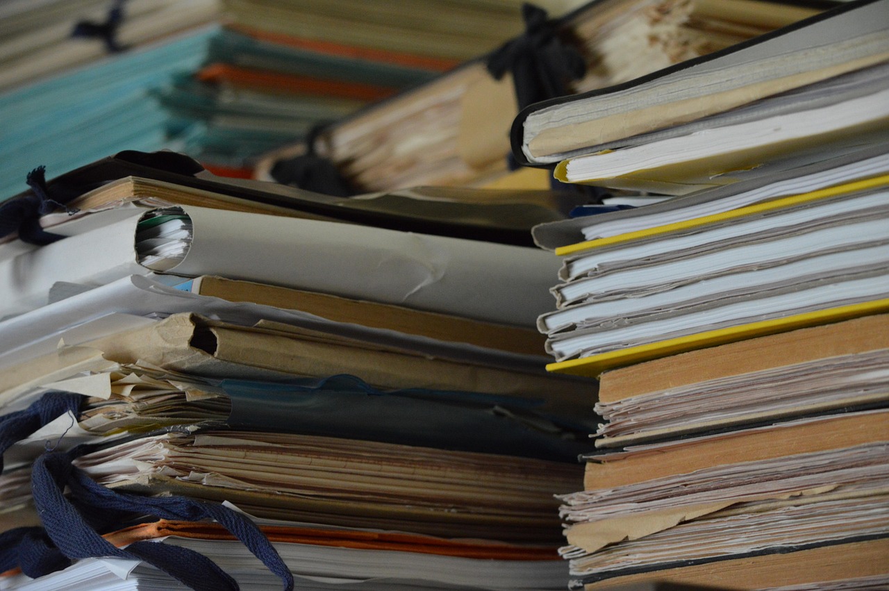 大量の書類やファイルが積み重なっている様子