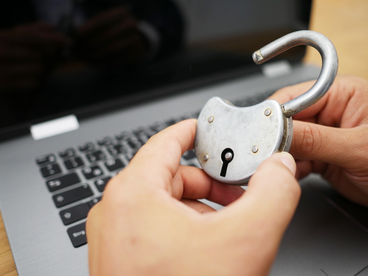 南京錠を手に持ち、ノートパソコンの上でセキュリティ対策をしているイメージ