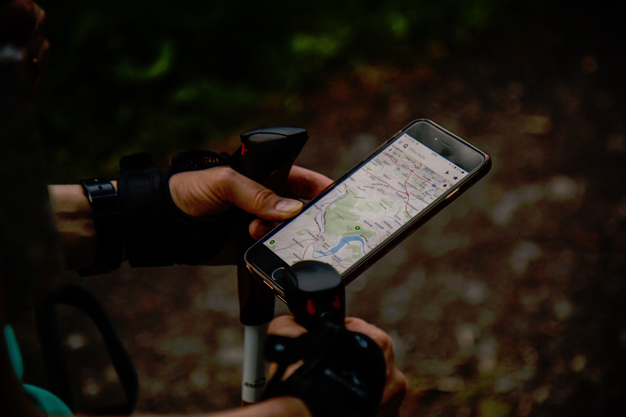 登山用ストックを握りながらスマートフォンの地図アプリを確認する登山者の手元