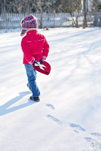 雪の積もった庭を歩く子どもの後ろ姿と足あと、日差しが作る影
