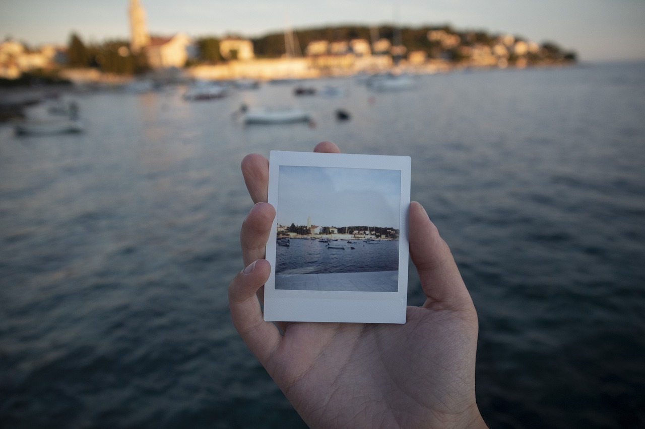 海辺の景色を写した一枚の写真を手に持っている様子