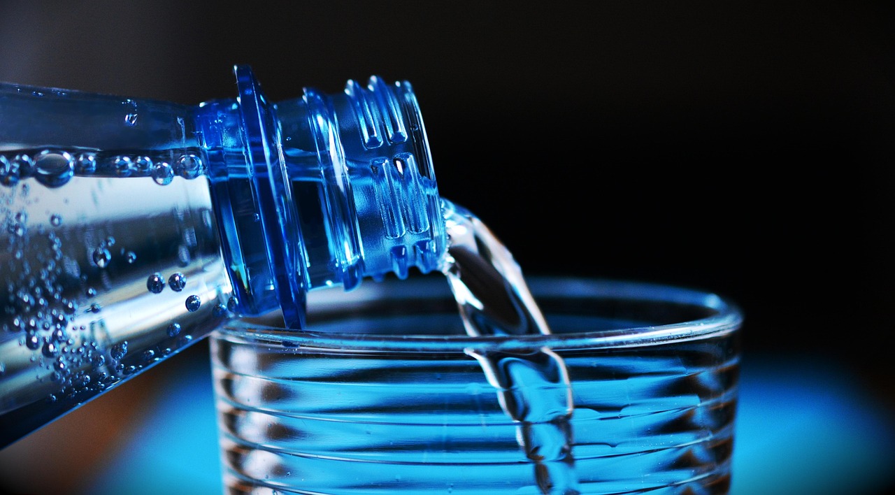 ペットボトルからグラスに水を注いでいるところ