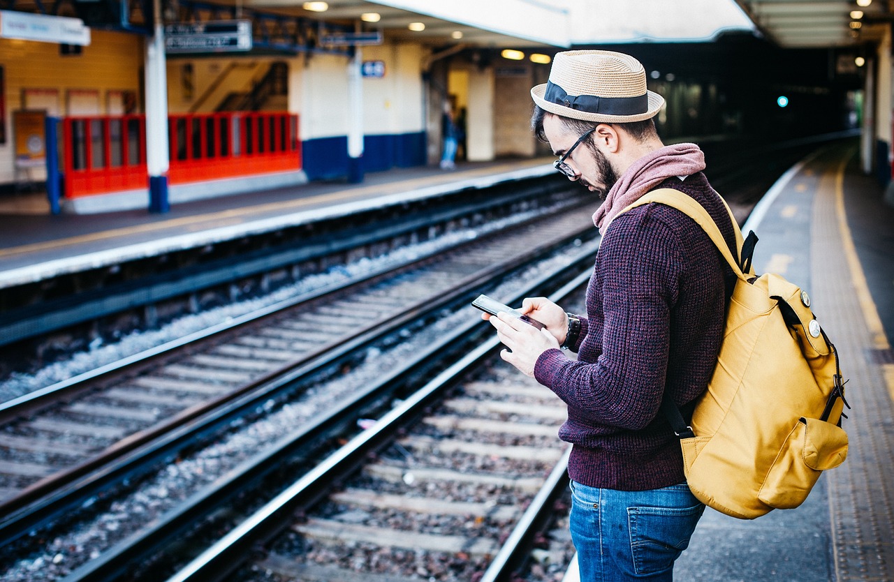 駅のホームでスマートフォンを操作する男性