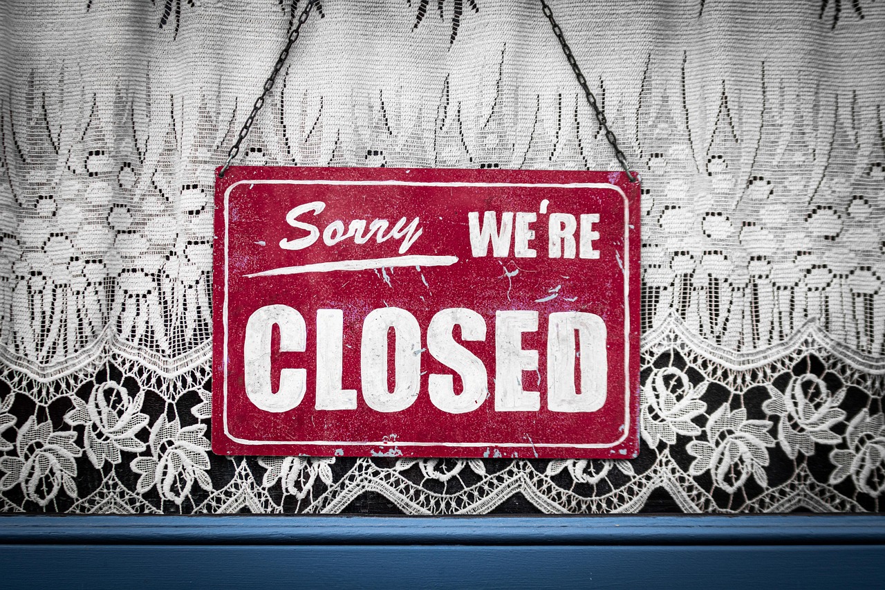 レースのカーテンの前に掛かった「Sorry we're closed」の赤い札