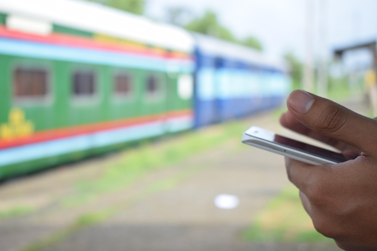 駅のホームでスマートフォンを持つ手