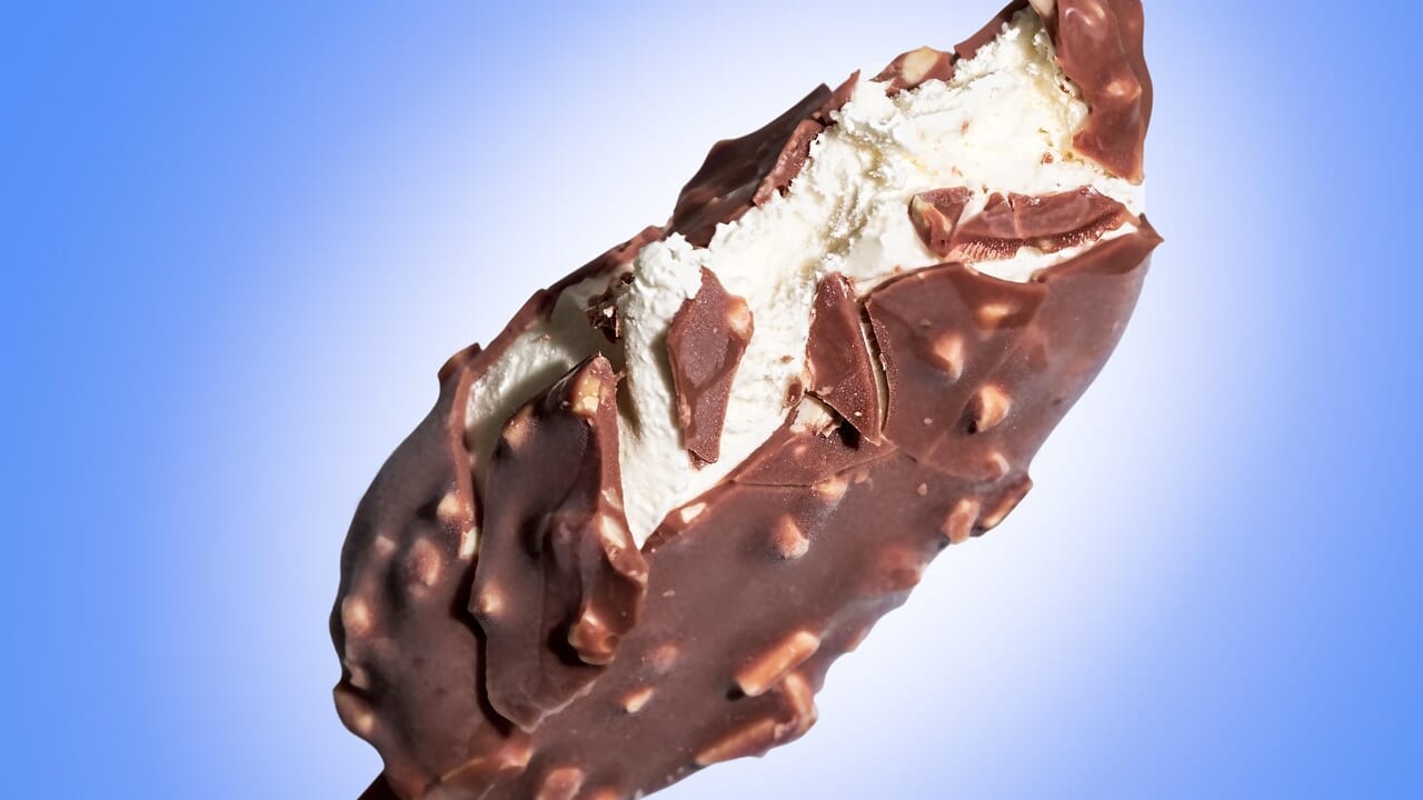 チョコレートがけのアイスバーをかじっているアップの写真、冷たいものばかり食べる夏の食生活のイメージ