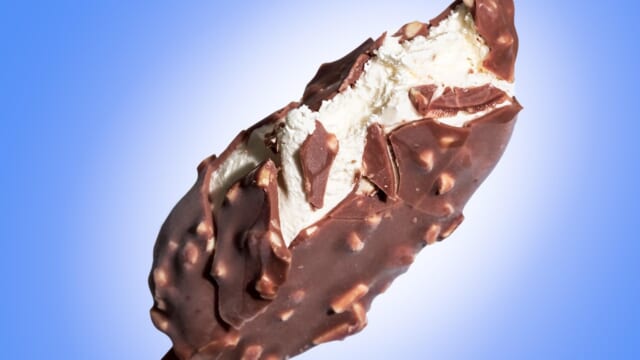 チョコレートがけのアイスバーをかじっているアップの写真、冷たいものばかり食べる夏の食生活のイメージ