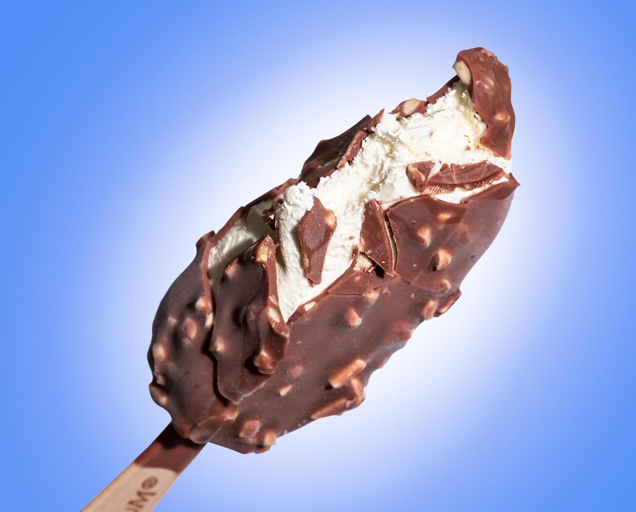 チョコレートがけのアイスバーをかじっているアップの写真、冷たいものばかり食べる夏の食生活のイメージ