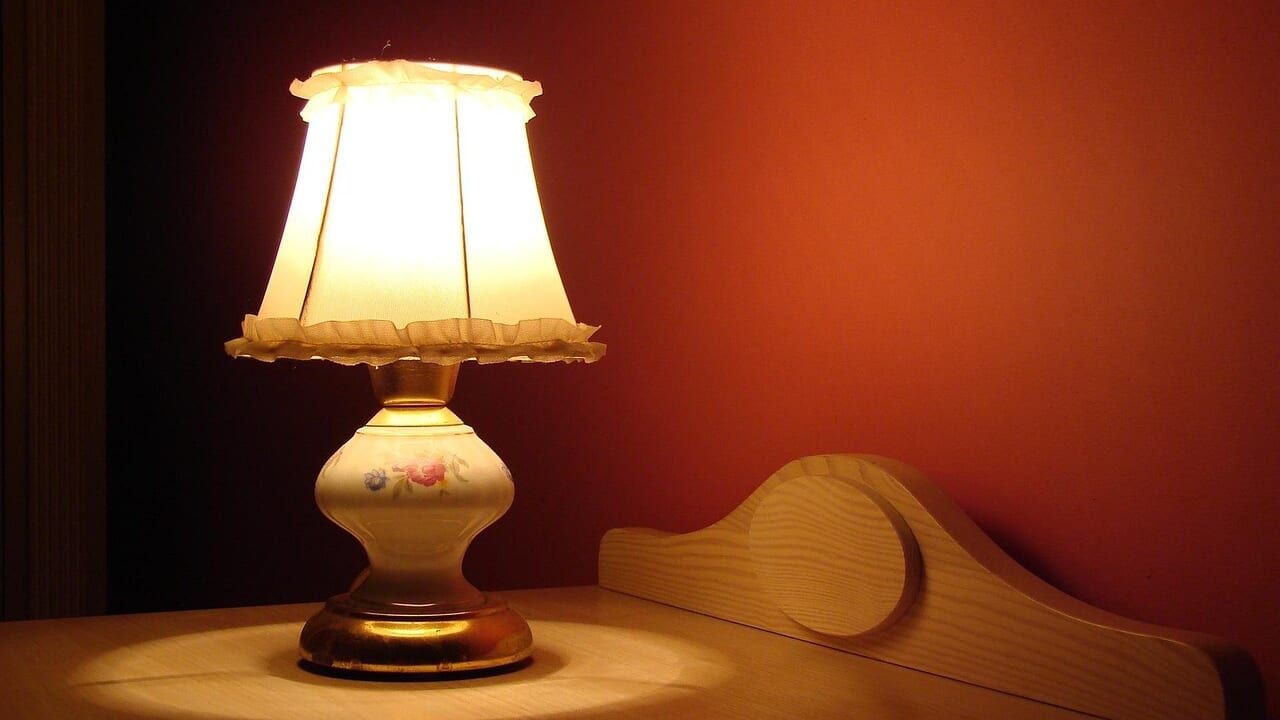 夜の部屋で、木の台の上のランプがやわらかく灯っている様子