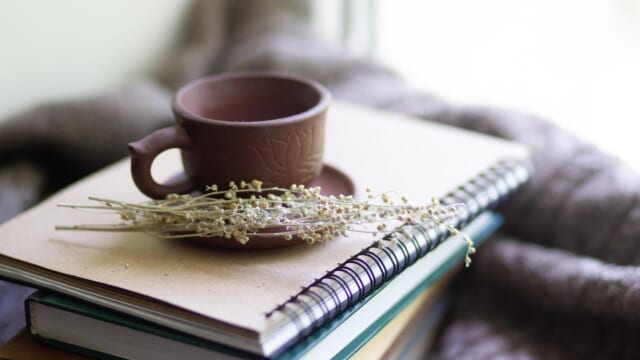 毛布の上に置いた本とお茶のカップ