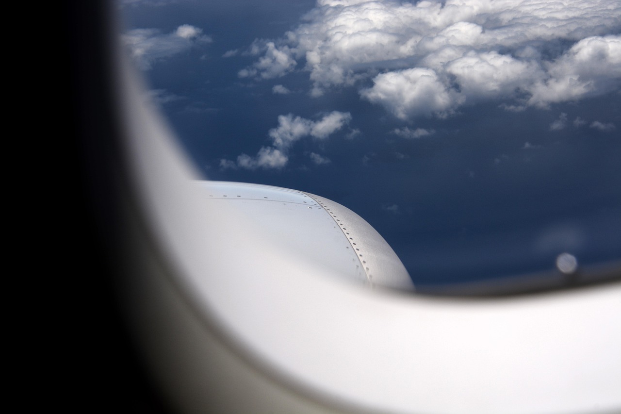 飛行機の窓から見た、エンジンの一部と雲の広がる空
