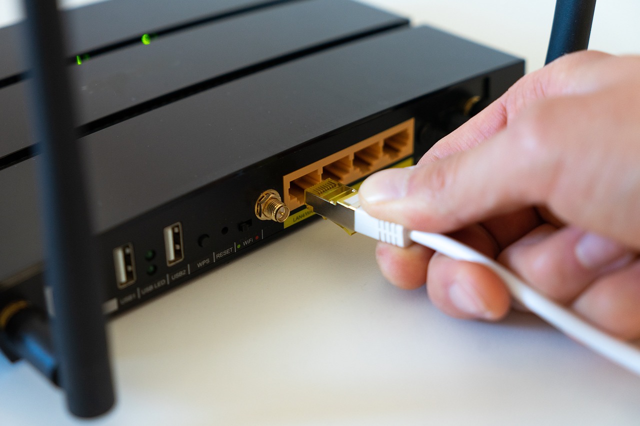 Wi-Fiルーターの差し込み口にケーブルを差す手