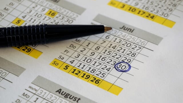年間カレンダーの上にペンが置かれ、6月30日に青い丸が付いている