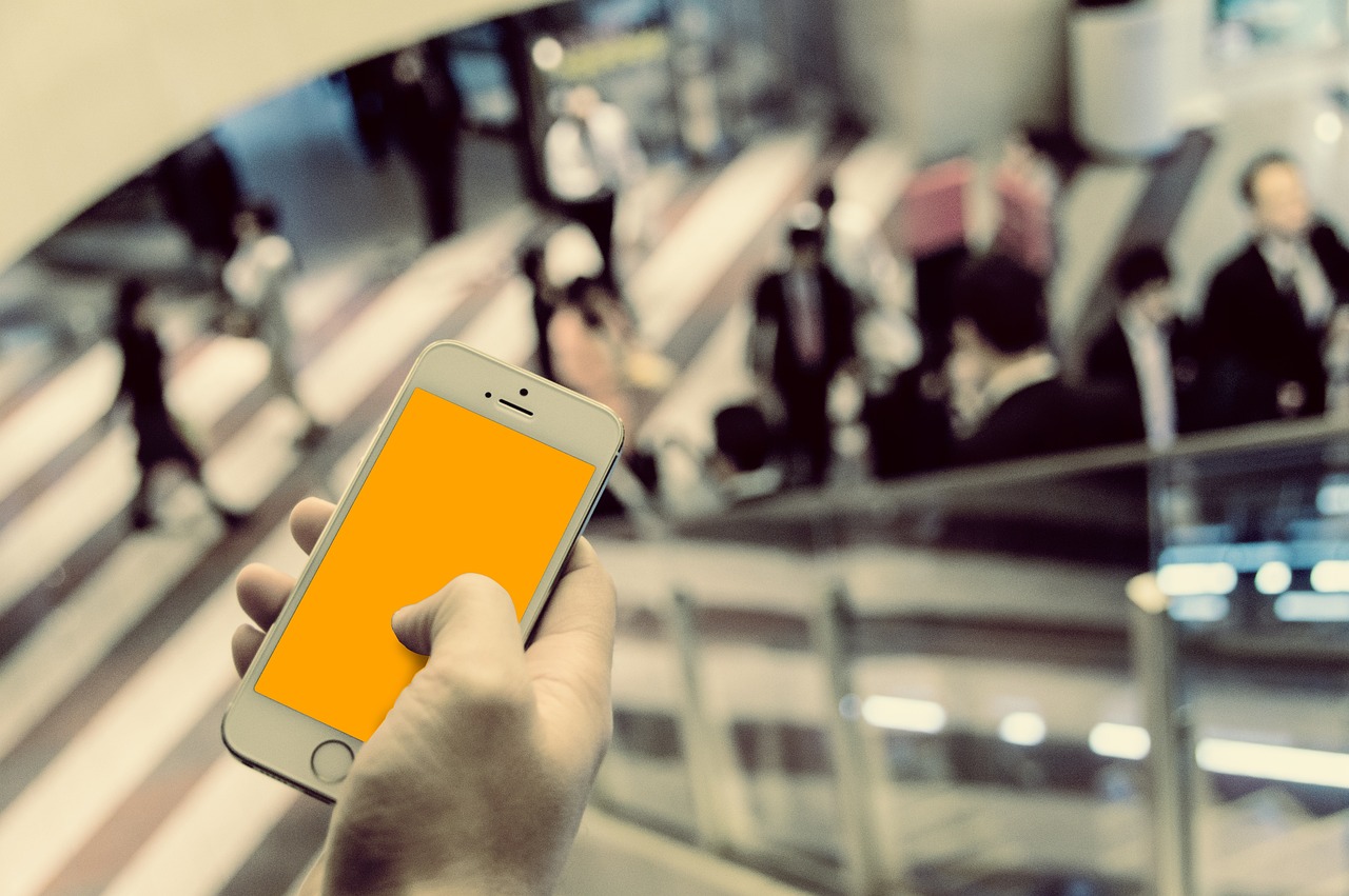 駅の通路でスマートフォンを片手に持って操作する手元