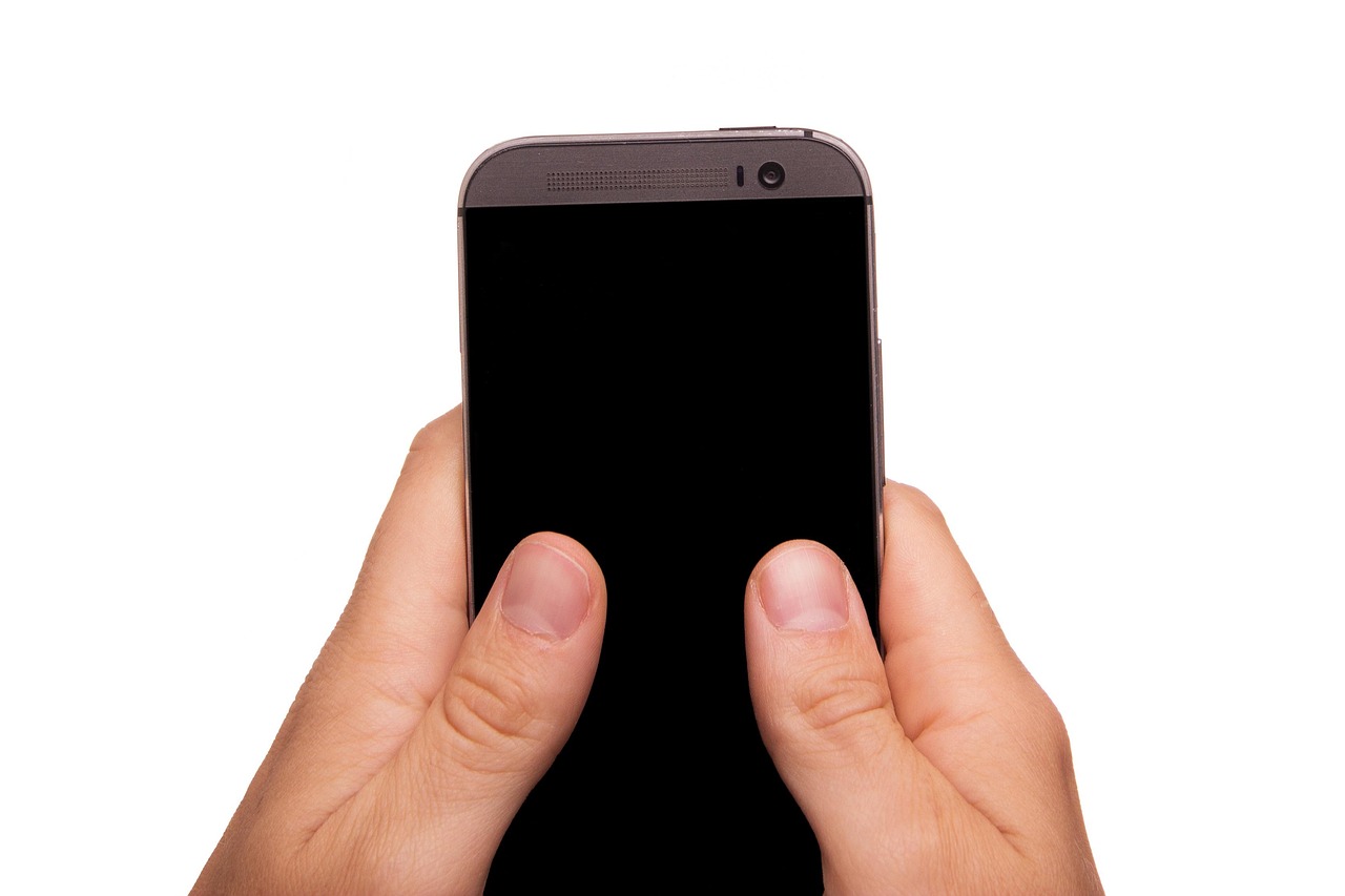 スマートフォンを両手で持って操作する手元