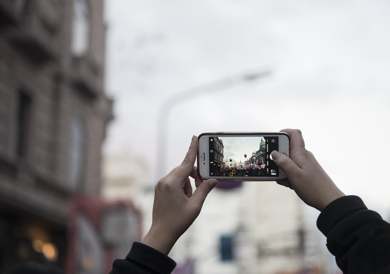 街の風景をスマートフォンで撮影している手元