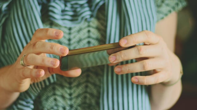 両手でスマートフォンを操作する人