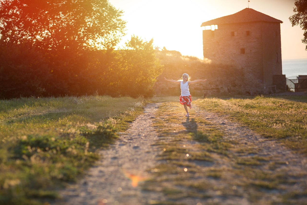 夕日の差す草地の小道を走る女の子