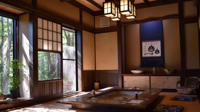 畳の和室にある、囲炉裏を囲む大きな座卓と座布団