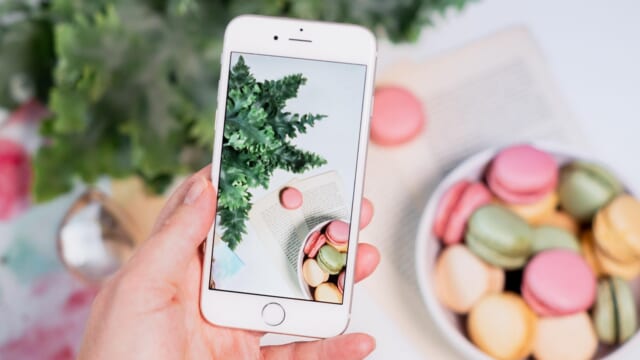 スマートフォンで机の上のお菓子を撮影する手元