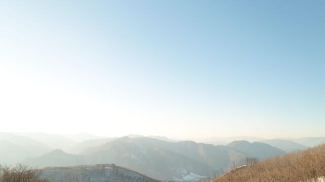 雪の残る山並みの上に広がる、冬の晴れた空